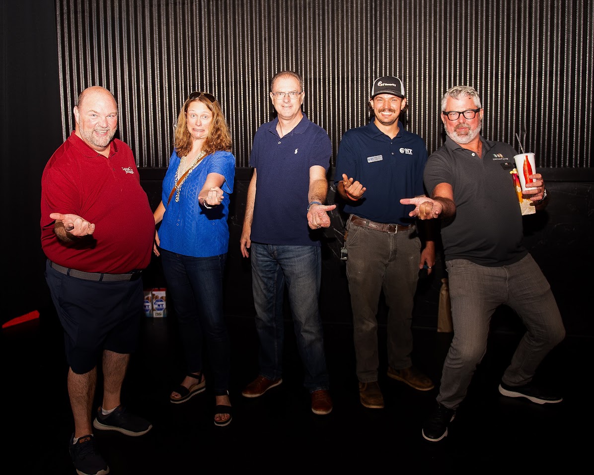 A group of Atlanta property managers and NT Security staff posing with Spider-Man web-slinger hand gestures at Family Movie Night