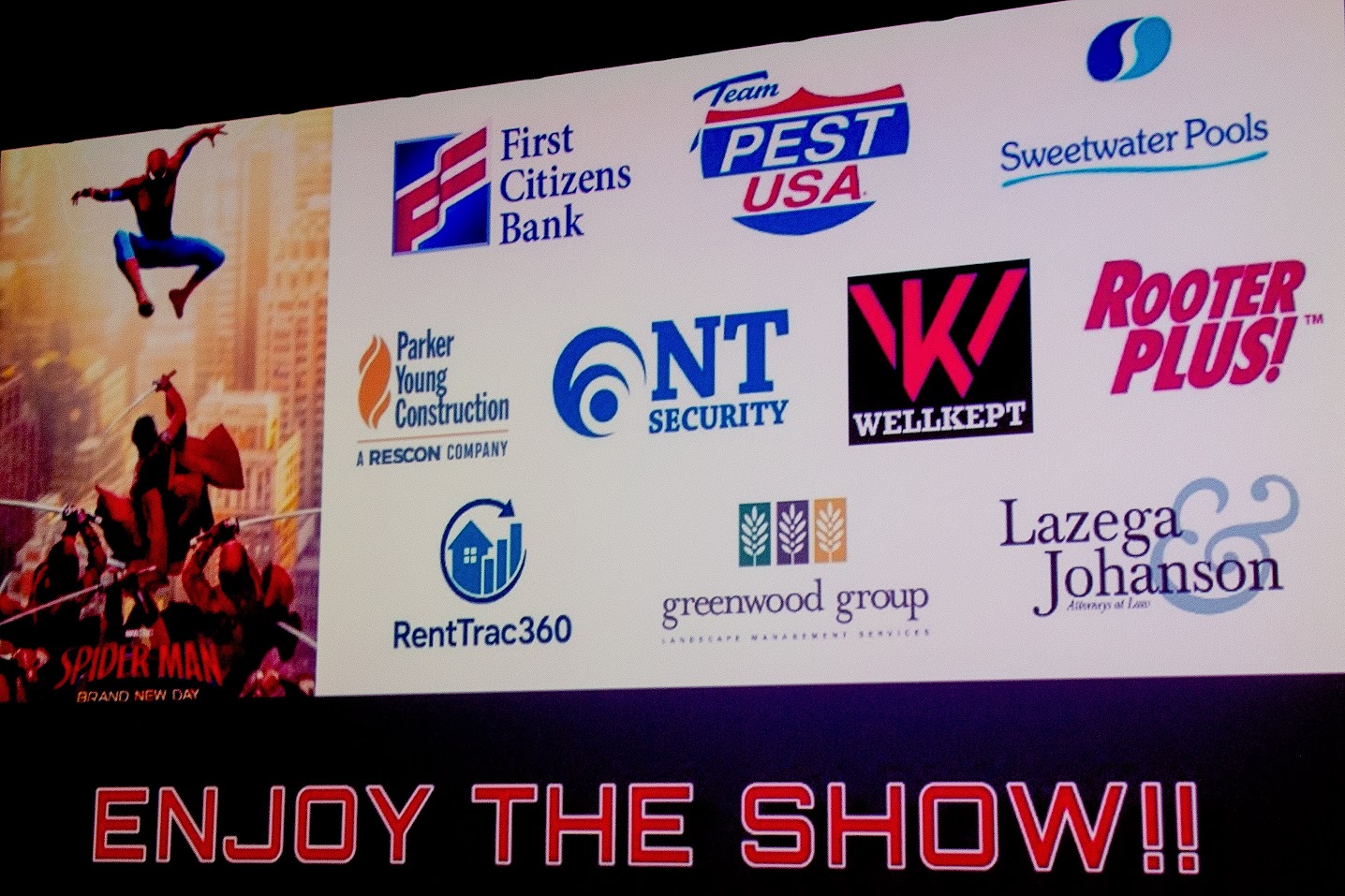 Sponsor logo slate on the movie screen showing NT Security alongside Team Pest USA, First Citizens Bank, Sweetwater Pools, Parker Young Construction, WellKept, Rooter PLUS, RentTrac360, Greenwood Group, and Lazega and Johanson
