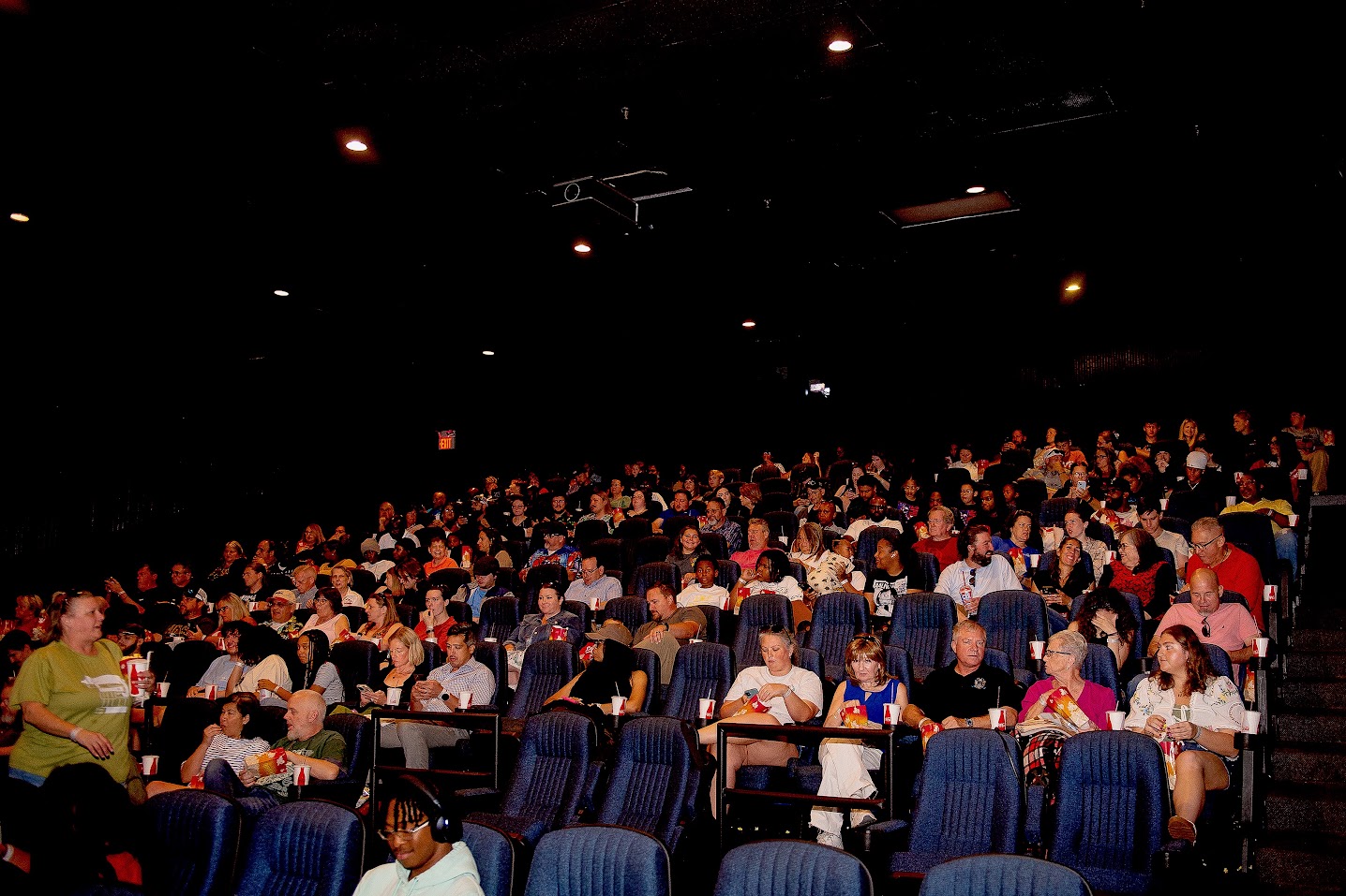 A packed movie theater auditorium of Atlanta property managers and their families at Team Pest USA Family Movie Night