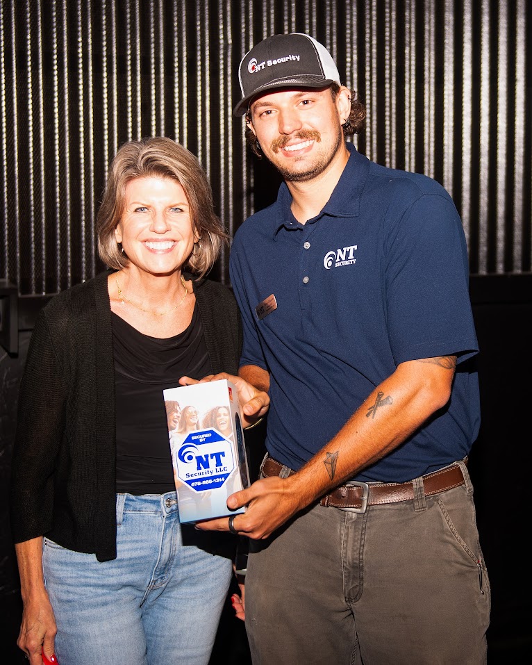 Vinny Orlando of NT Security handing an NT Security branded JBL Flip 6 speaker to a winning attendee at Family Movie Night